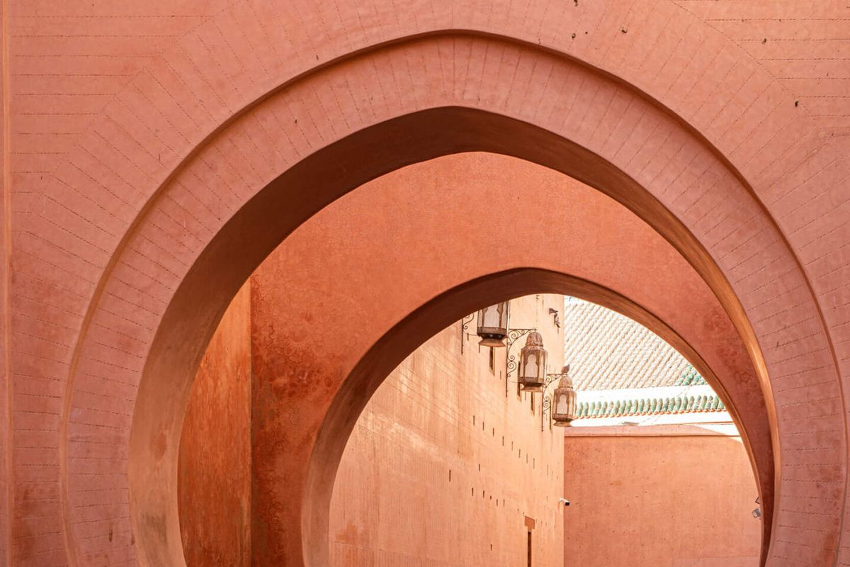 Passage with arches and a person walking in a warm-toned architectural setting